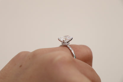 Diamond ring on a finger against a plain background