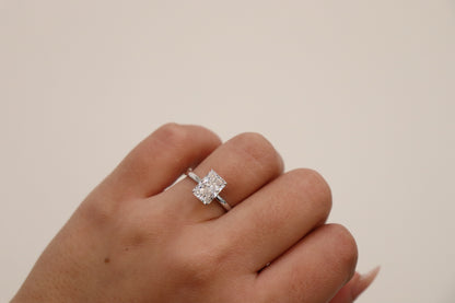 Diamond ring on a finger against a plain background