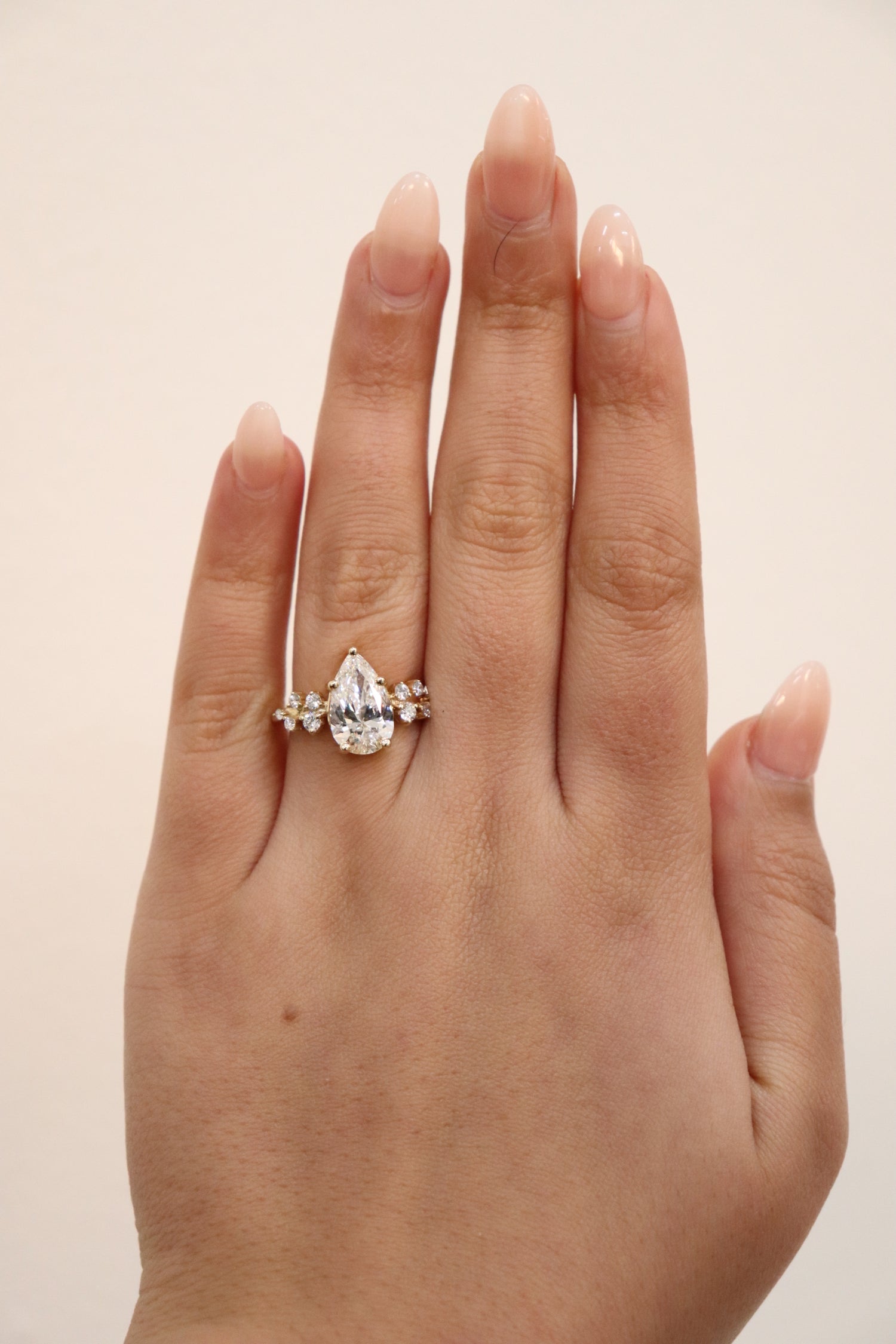 Hand wearing a diamond ring on a plain background