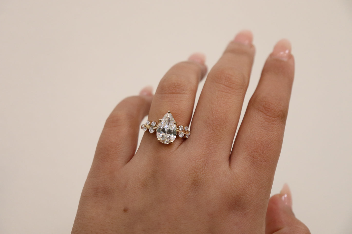 Hand wearing a diamond ring on a plain background