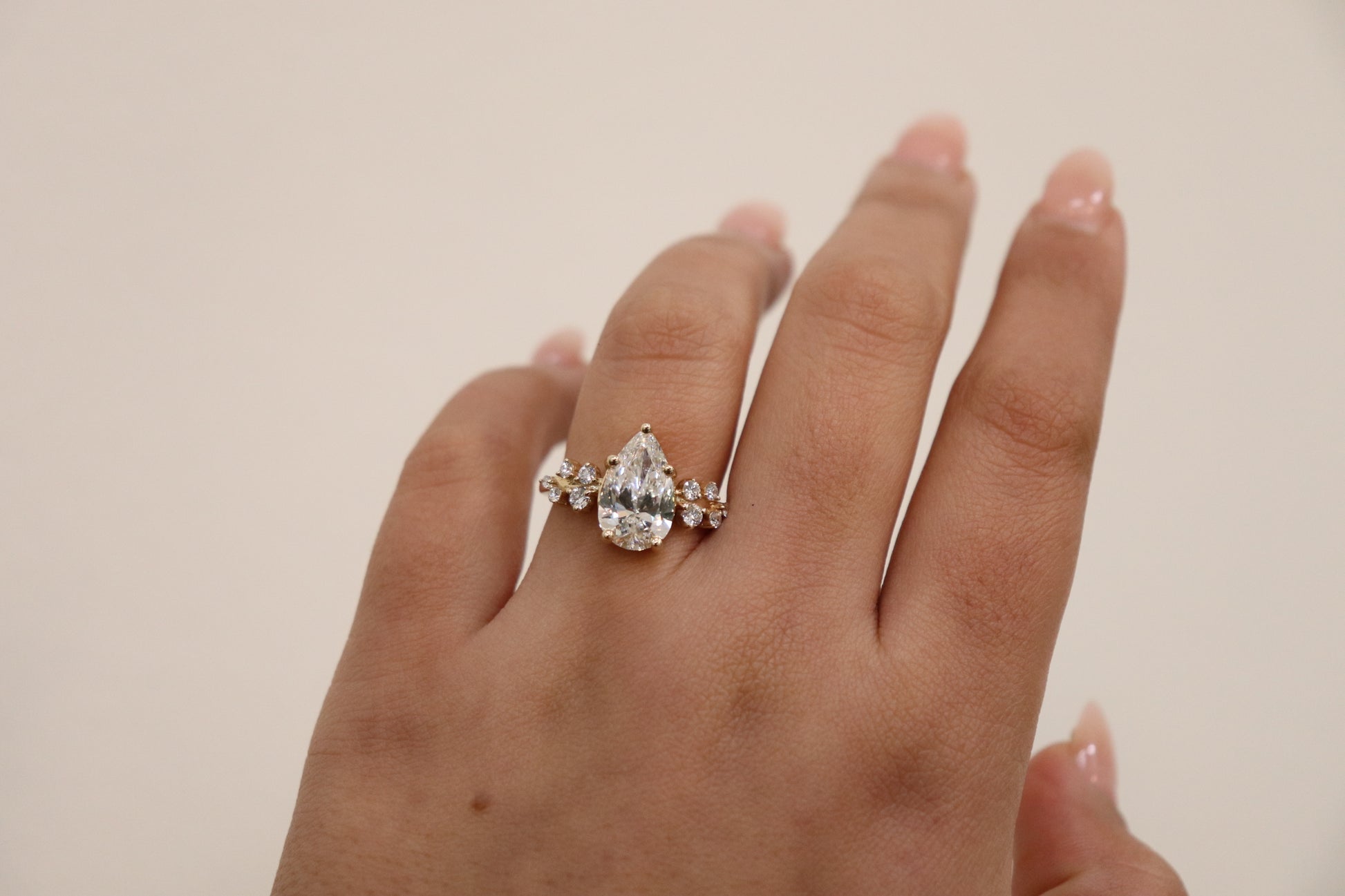 Hand wearing a diamond ring on a plain background