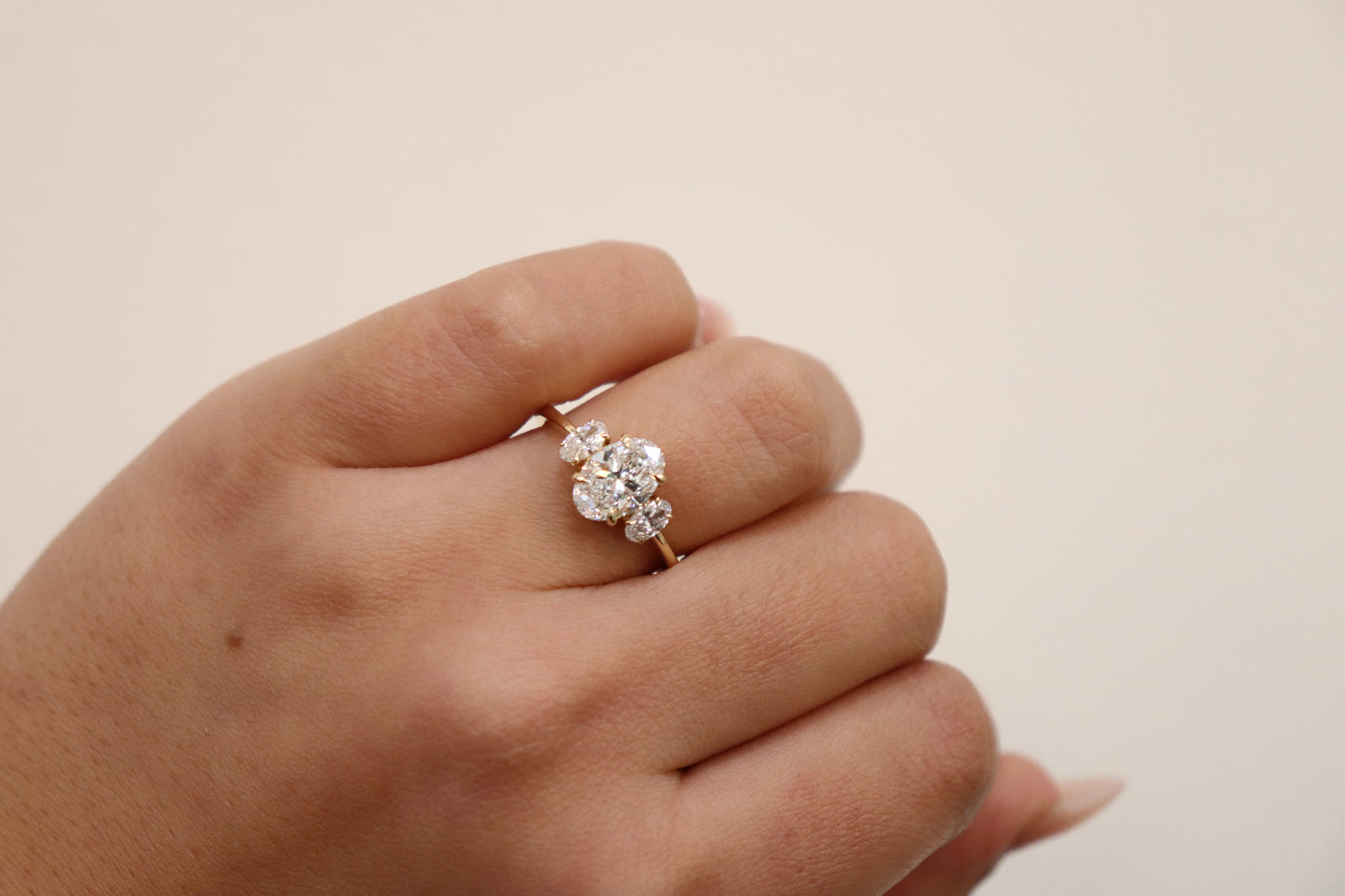 Hand wearing an Oval Trilogy Engagement Ring with Ovals on the side