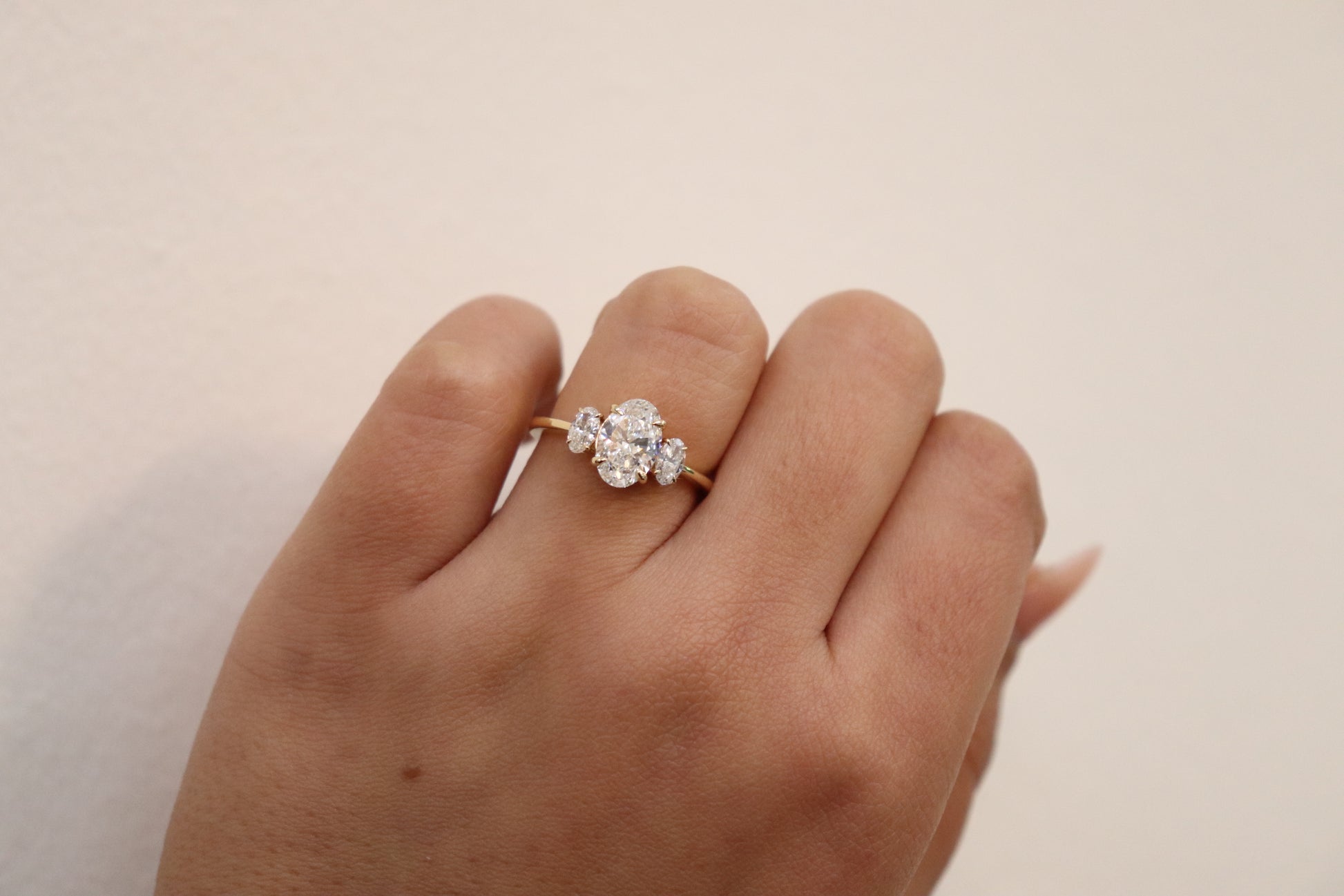 Hand wearing an Oval Trilogy Engagement Ring with Ovals on the side