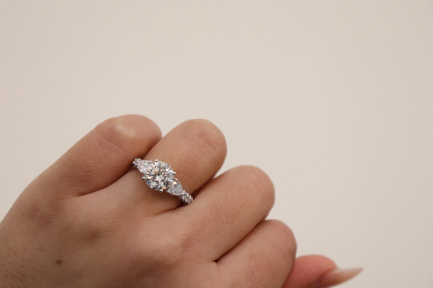 Diamond ring on a finger against a plain background