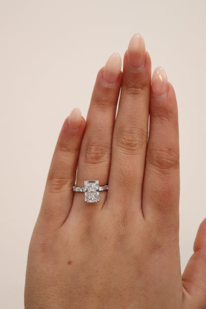Radiant cut Diamond ring on a hand against a plain background