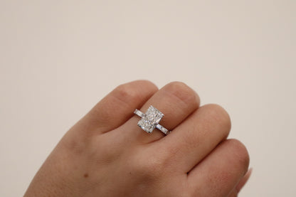 Radiant cut Diamond ring on a finger against a plain background