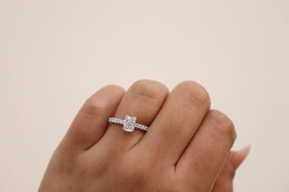 hand wearing a radiant cut diamond engagement ring with triple pavè band on with a neutral background